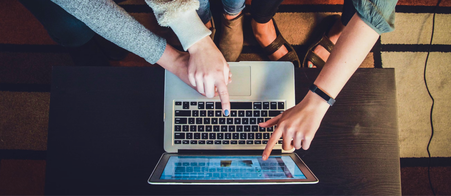 three people pointing at a laptop screen